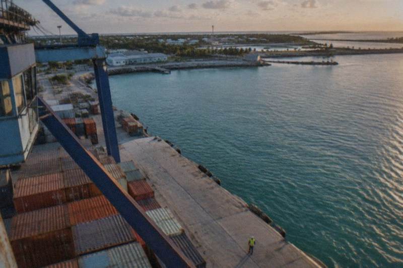 A high-speed ferry seen from a low dock angle at a Fort Lauderdale marine terminal, bow pointed toward open water, no people, no logos, no readable text.